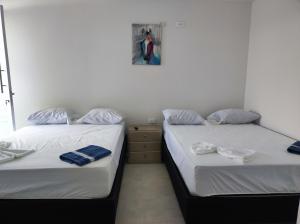 2 Betten nebeneinander in einem Zimmer in der Unterkunft Apartamentos Villa Leonor in Coveñas