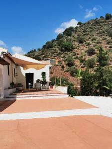 een huis met een patio met een berg op de achtergrond bij Finca el Fuenton in Málaga