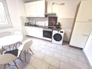 a kitchen with a washing machine and a table and chairs at Monteurzimmer am Bahnhof Biesenthal - 2 große Apartments in Biesenthal