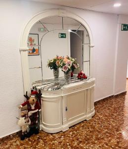 un tocador con flores en una habitación con espejo en Ana Belén, en Granada