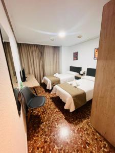 um quarto de hotel com duas camas e uma cadeira em Ana Belén em Granada