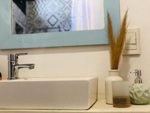 a bathroom sink with a mirror and a vase with grass at Cielos de Maimará in Maimará +34 photos