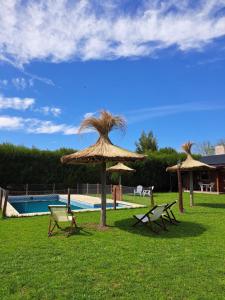 2 sillas y sombrillas junto a una piscina en CABAÑAS LOS ARRAYANES en Chascomús