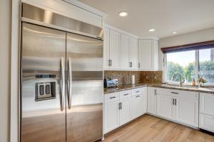 uma cozinha com armários brancos e um frigorífico de aço inoxidável em Huntington Beach Condo - Walk to the Ocean! em Huntington Beach