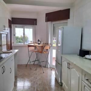 eine Küche mit einem Tisch und einem Kühlschrank in der Unterkunft Casa das Borboletas in Évora