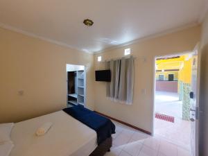 a bedroom with a bed and a television and a balcony at Pousada Villa Coelho in Camaçari