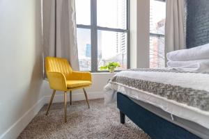a bedroom with a yellow chair in front of a bed at McCormick Place 420 friendly 2br/2ba with optional parking for up to 6 guests in Chicago