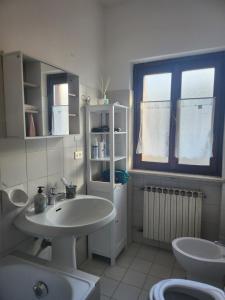 uma casa de banho com um lavatório, um WC e uma janela. em Margiolà em Calalzo