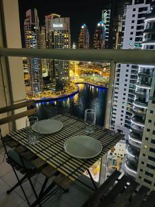 a table with wine glasses on a balcony at night at Amazing 1 bedroom apt in Marina in Dubai