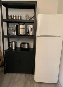 a black shelf with a microwave and a refrigerator at Très joli appartement à Puteaux centre ville in Puteaux