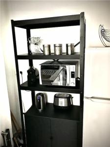 a black shelf with a microwave on it next to a refrigerator at Très joli appartement à Puteaux centre ville in Puteaux