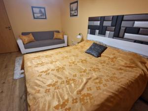 a bedroom with a large bed and a couch at Centrum Business Apartman Szekszárd in Szekszárd