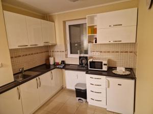 a kitchen with white cabinets and a microwave at Centrum Business Apartman Szekszárd in Szekszárd