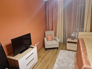 a bedroom with a television and a chair and a bed at Centrum Business Apartman Szekszárd in Szekszárd