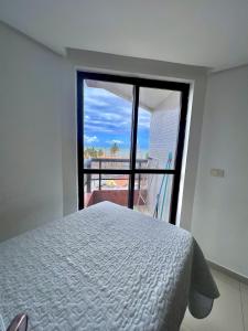 a bedroom with a bed and a large window at MARINAS PRAIA Flat in João Pessoa