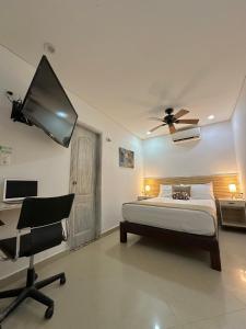 a bedroom with a bed and a desk and a tv at Hotel La Magdalena in Cartagena de Indias