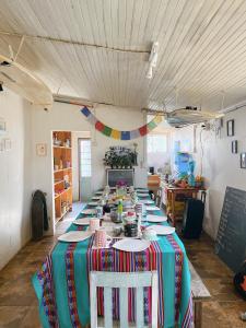 einen langen Tisch mit Tellern und Geschirr in einem Zimmer in der Unterkunft SURFHOUSE Pichilemu in Pichilemu