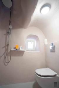 a white bathroom with a toilet and a window at Bird Nest-Santorini Cave houses in Fira