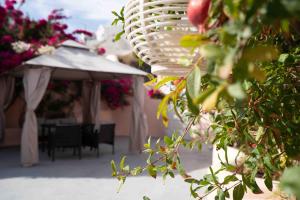 a patio with a table and an umbrella and flowers at Bird Nest-Santorini Cave houses in Fira