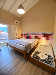a bedroom with two beds and a large window at Pousada Toca da Praia in Maresias