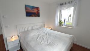 un letto bianco in una camera da letto con due finestre di FeWo "Leuchtturmliebe" 