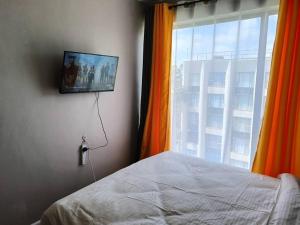 1 dormitorio con 1 cama y TV en la pared en Legatus Cozy Homes, en Ongata Rongai 