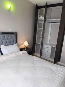 a bedroom with a large white bed and a lamp at Legatus Cozy Homes in Ongata Rongai 