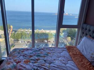 a bedroom with a bed and a view of the ocean at Blue Waves Abu Halifa أمواج الخليج الزرقاء in Kuwait