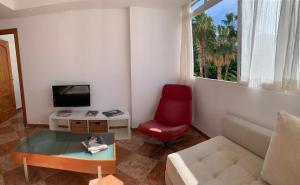 sala de estar con sofá y silla roja en Los Guindos, en Málaga
