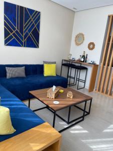 a living room with a blue couch and a table at Cosy appartement à Ain Diab beach in Casablanca