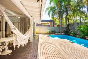a porch with a hammock and a swimming pool at Praia Mole, Florianopolis, paraiso. in Florianópolis