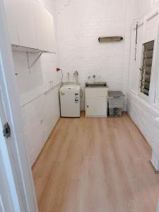 a kitchen with white walls and a wooden floor at three bedroom house within walking distance to light rail station in Sydney