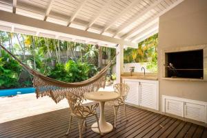 um alpendre com uma rede de descanso, uma mesa e cadeiras em Praia Mole, Florianopolis, paraiso. em Florianópolis