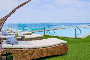 a group of wicker chairs and tables next to a pool at Hotel Gavina Costa Mar in Iquique