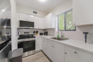 a white kitchen with a sink and a stove at Steps Away from Calle Ocho in Little Havana in Miami