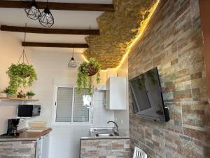 cocina con fregadero y TV en la pared en Casa entre Rocas Setenil, en Setenil