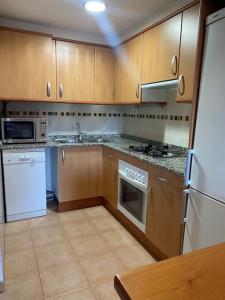 - une cuisine avec des placards en bois et des appareils blancs dans l'établissement Apto en Campo Valle de Benasque 2 dormitorios Wifi, à Campo