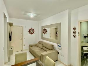 a living room with a couch and a clock on the wall at APARTAMENTO PRAIA BOMBINHAS in Bombinhas