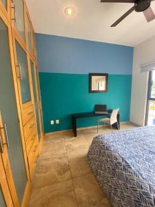 1 dormitorio con pared azul, cama y escritorio en Oceanview Condo - Club Cerralvo, en El Sargento