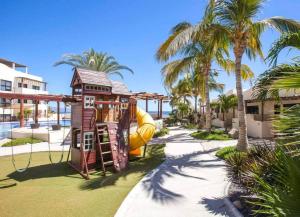 un parque infantil en un complejo con palmeras en Oceanview Condo - Club Cerralvo, en El Sargento