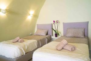 - 2 lits dans une chambre avec des oreillers roses dans l'établissement Santorini Oasis- Cave House, à Fira