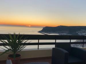 a view of a sunset from a balcony with a plant at Apartment with a stunning view over Sesimbra in Sesimbra
