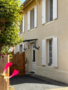 a house with white shutters and a wooden gate at Maison 15 in Sauternes