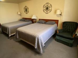 a hotel room with two beds and a chair at The Willows Motel in Wilbur