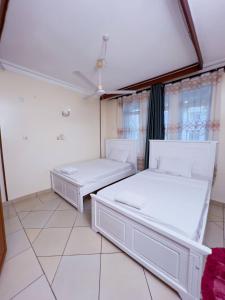 2 camas en una habitación con suelo y ventanas blancos en Majestic Homes, en Nyali