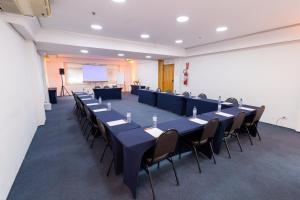 a conference room with tables and chairs and a screen at Sables Hotel Guarulhos in Guarulhos