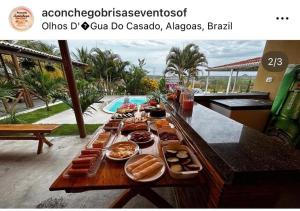 a buffet of food on a table next to a pool at Pousada Aconchego Brisas e Ventos in Olho D’Água do Casado