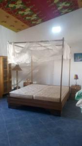 ein Schlafzimmer mit einem großen Bett mit Baldachin in der Unterkunft Chez John et Élisa in Ndangane