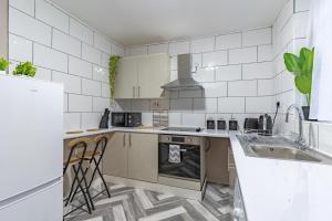 uma cozinha com paredes de azulejos brancos e electrodomésticos brancos em STAYZED R - Urban Oasis NG7, Walking Distance From City Centre & Lots of Amenities - Large bedrooms, Perfect for Work, Tourism, Family and Contractors - Long Stays Welcome em Nottingham