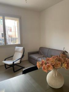 una sala de estar con sofá y un jarrón con flores sobre una mesa en MAISON ANZIO E ROSA, en Rávena